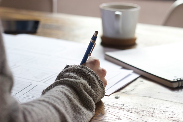 Hand holding a pen writing on paper